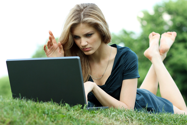 Молодая девушка с ноутбуком в парке