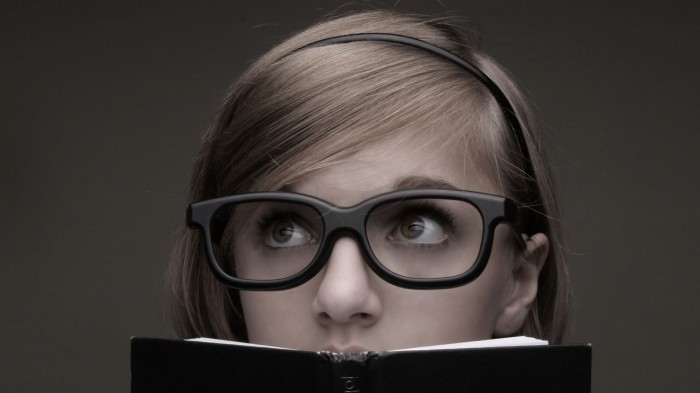 nerdy-girl-looking-over-a-book-700x393